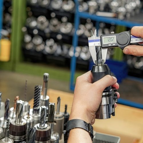 Measuring a cutting tool with a caliper for a CNC machine tool.